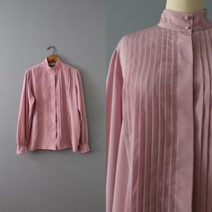 Vintage romantic essential minimalist secretary blouse in wisteria color. Pleated front, high neck, billowy sleeves. Silky polyester material. ⊰ Measurements: Fits like medium, large: 15" shoulders 42" bust 26" length 25" sleeves Tag: Dana Alexander Circa 1990s Condition: excellent! ⊰ Visit the shop: adriancompany.etsy.com ⊰ Instagram: @adriancovintage @the_veiled_ghost Elegant Fall Blouse With Pintucks, Elegant Pintucks Blouse For Fall, Spring Formal Pleated Top, Feminine Spring Blouse With Pintucks, Spring Feminine Blouse With Pintucks, Feminine Pleated Blouse For Work, Feminine Office Blouse With Pleated Sleeves, Elegant Pintuck Tops For Workwear, Elegant Pintuck Tops For Work