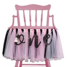 a pink rocking chair with some black and white tulle skirt hanging from it's legs