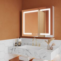 a bathroom with marble counter tops and orange walls, along with an illuminated mirror above the sink