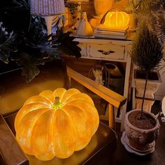 a large pumpkin sitting on top of a wooden table next to potted plants and other decorations