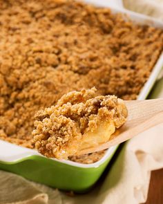 a spoon full of food sitting in a green casserole dish on top of a table