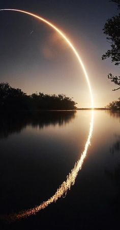 an object is flying in the air over water at night with its reflection on the surface