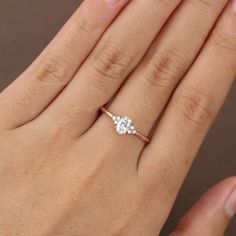 a woman's hand with a diamond ring on top of her finger and the other hand holding an engagement ring