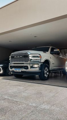 two trucks are parked in front of a parking garage with their lights on and the door open