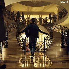 a man walking up the stairs in front of a spiral staircase with iron railings