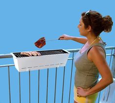 a woman standing on a balcony grilling meat