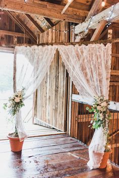 two vases with flowers and greenery are sitting on the floor in front of a wooden wall