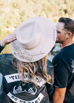 a man and woman kissing each other while standing next to each other wearing cowboy hats