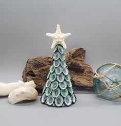 there is a small christmas tree next to some seashells and a starfish