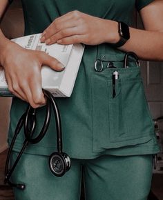 a woman in green scrubs is holding a book and a stethoscope