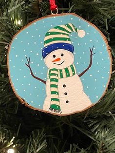 a wooden ornament with a snowman on it hanging from a christmas tree