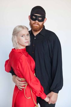 a man and woman dressed up as masked characters pose for a photo together in front of a white background