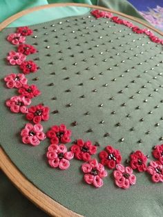 a close up of a piece of cloth with red flowers on it and beading