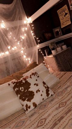 a bed with some lights on the headboard and pillows in front of it,