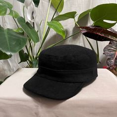 a black hat sitting on top of a table next to a potted green plant