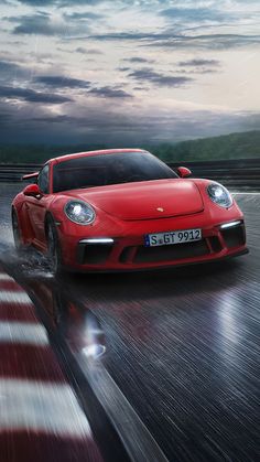 a red sports car driving on a wet road at dusk with clouds in the background