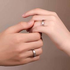 two hands holding each other with wedding rings on top of one another's fingers