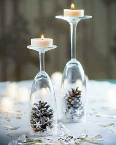 two wine glasses filled with snow and pine cones are sitting on a table next to each other