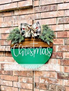 a christmas sign hanging on the side of a brick building with wreaths and bows