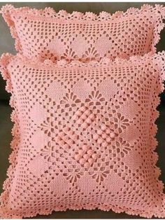 two pink crocheted pillows sitting next to each other