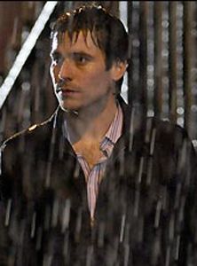 a man is standing in the rain with his hand on his hip and looking off into the distance