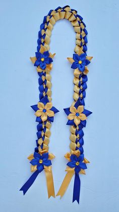 a blue and yellow ribbon with gold bows on the end is attached to a white wall