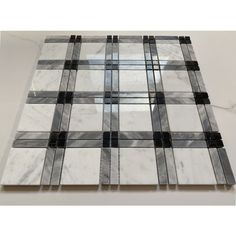 a white and black marble mosaic tile on a table with grey lines in the middle