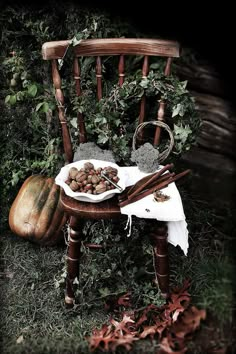 a wooden chair sitting in the grass next to a bowl of nuts and cinnamon sticks