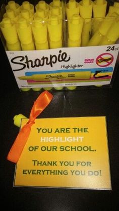 a box of sharpie sticks with an orange ribbon on it next to a sign that says, you are the highlight of our school thank you for everything you do