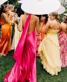 a group of women standing next to each other in dresses and holding white umbrellas