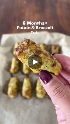 a person holding up a piece of food in front of some small bites on parchment paper