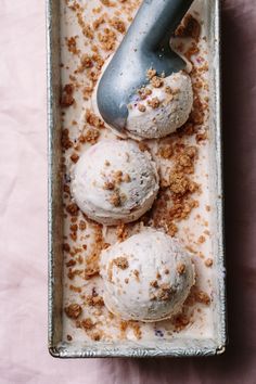 three scoops of ice cream in a pan with crumbs on the top