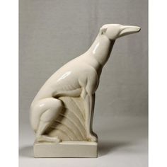 a white ceramic sculpture of a dog sitting on its hind legs and looking to the side