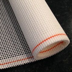 a roll of white mesh with an orange line on the side and black background behind it