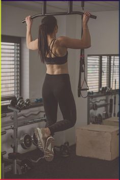 a woman doing pull ups in a gym