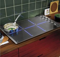 a stove top with a pan on it next to a cutting board and utensils