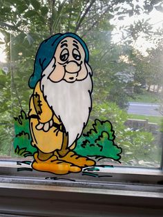 a stained glass window with an image of a gnome sitting on the ground in front of trees