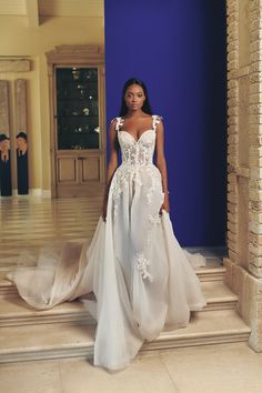 a woman in a white wedding dress standing on the floor next to a blue wall