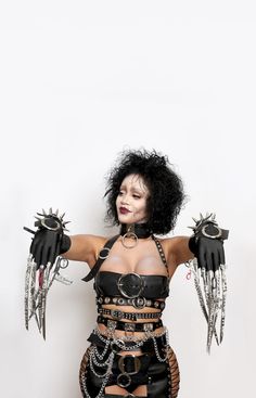 a woman dressed in black with chains and spikes on her arm, holding two hands