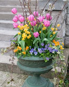 a large vase filled with lots of flowers on top of a cement step next to steps