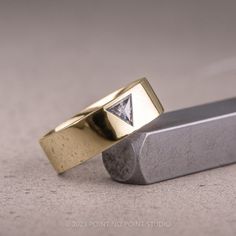 two gold wedding bands with a diamond in the middle on top of a metal block