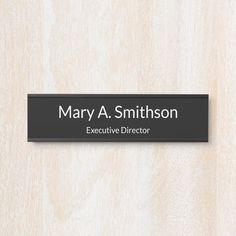 a black and white name plate on a wooden wall that says, mary a smithon executive director