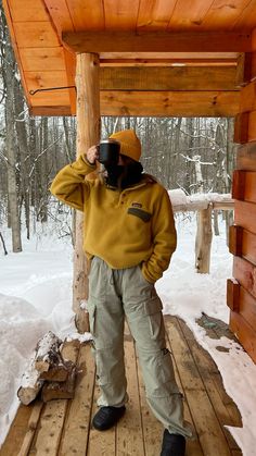 a person standing on a wooden platform in the snow holding a camera up to their face