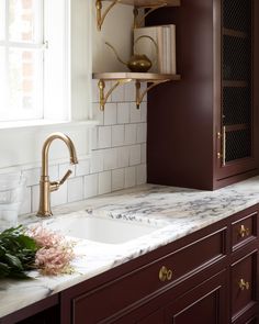 a kitchen with marble counter tops and dark wood cabinets, gold faucet handles