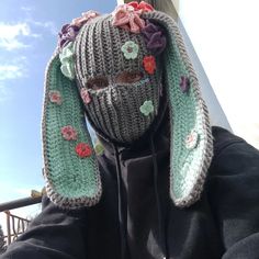 a person wearing a knitted bunny hat with flowers on it's ears and nose