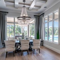 an elegant dining room with chandelier and large windows overlooking the pool in the background