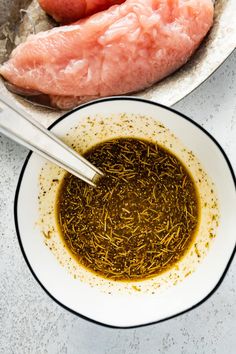 a white bowl filled with green tea next to meat on top of a countertop