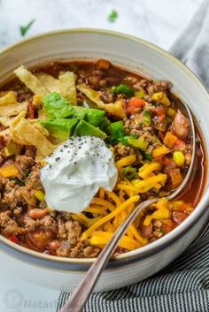 a bowl of chili soup with sour cream and tortilla chips