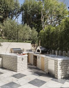 an outdoor kitchen with grill, sink and table