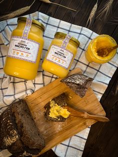 two jars of honey sit next to bread on a cutting board